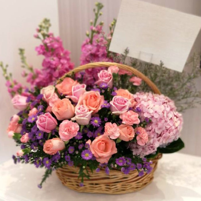 Giỏ hoa khai trương màu hồng trên nền hoa tím nổi bật